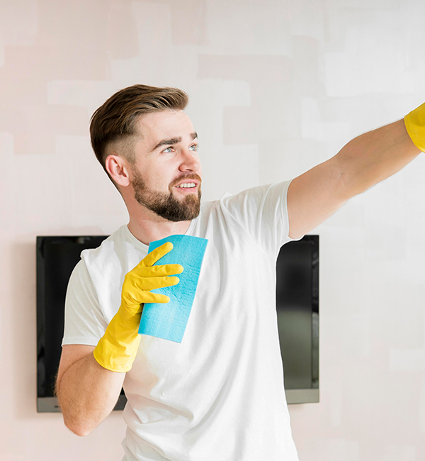 A man in rubber gloves holds a cleaning cloth, ready to clean, with a yellow glove on his other hand.