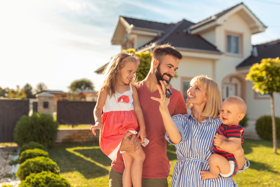 A happy family standing in front of their new home, smiling and looking excited for the future.