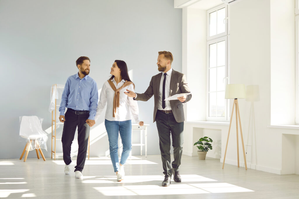 Three people walking in a white empty room.