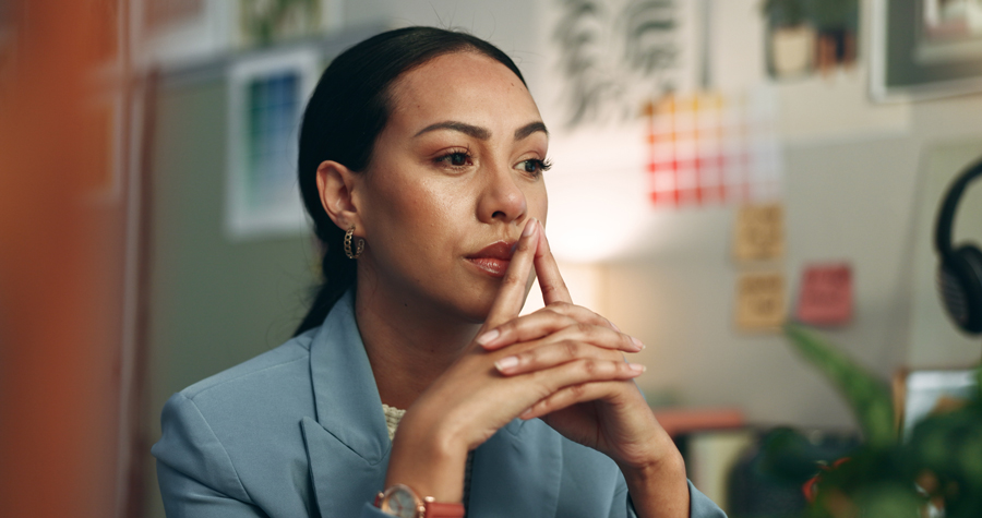 A young girl in a business suit sitting at a desk.